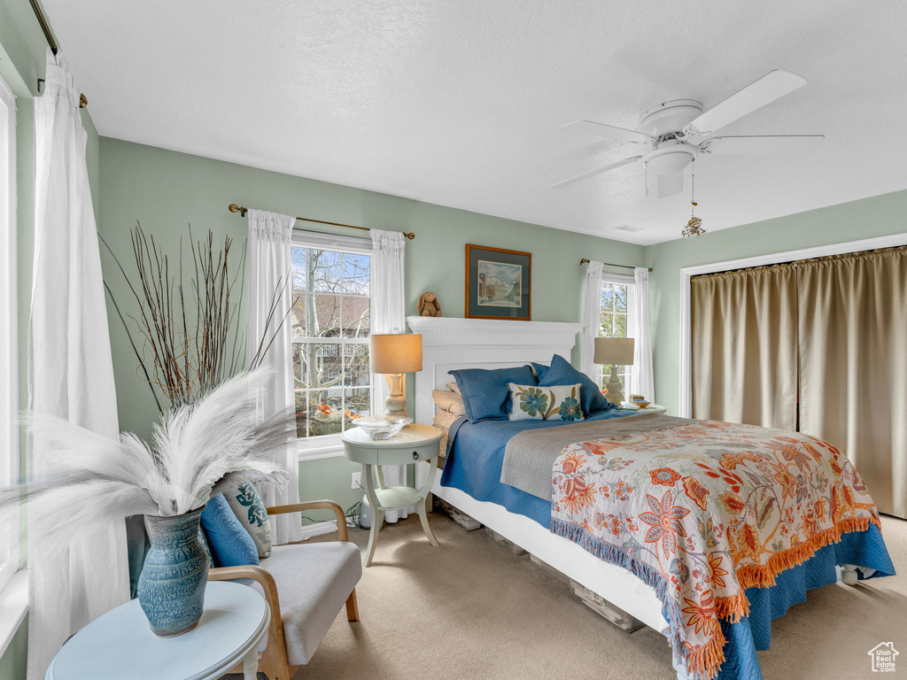 Bedroom featuring carpet flooring, a ceiling fan, and multiple windows