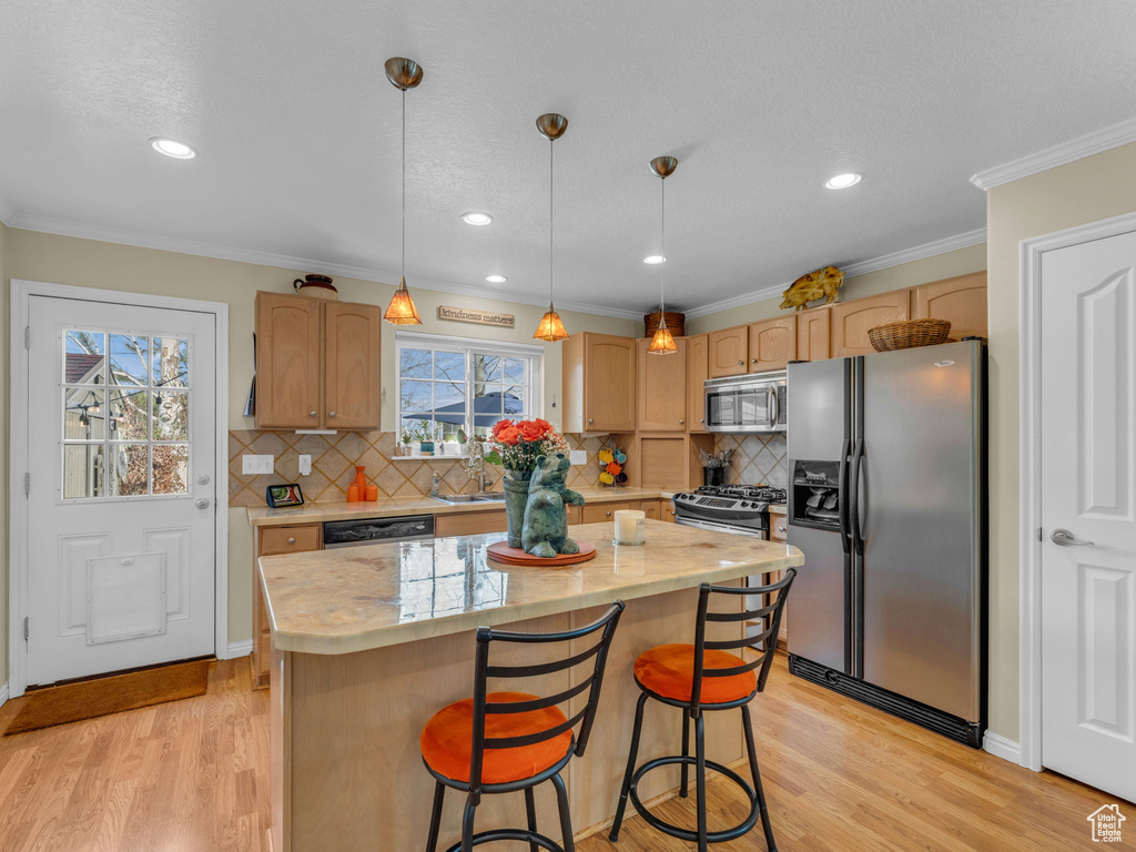 Kitchen with light wood-type flooring, a sink, appliances with stainless steel finishes, and a center island