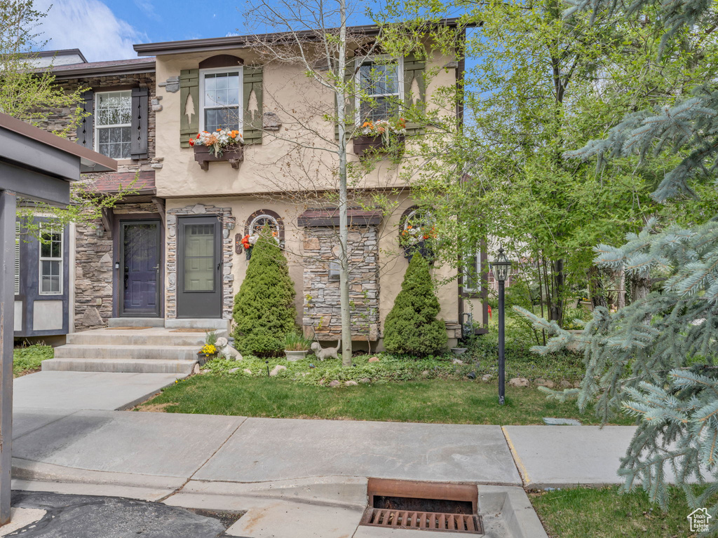 Townhome / multi-family property featuring stucco siding and stone siding