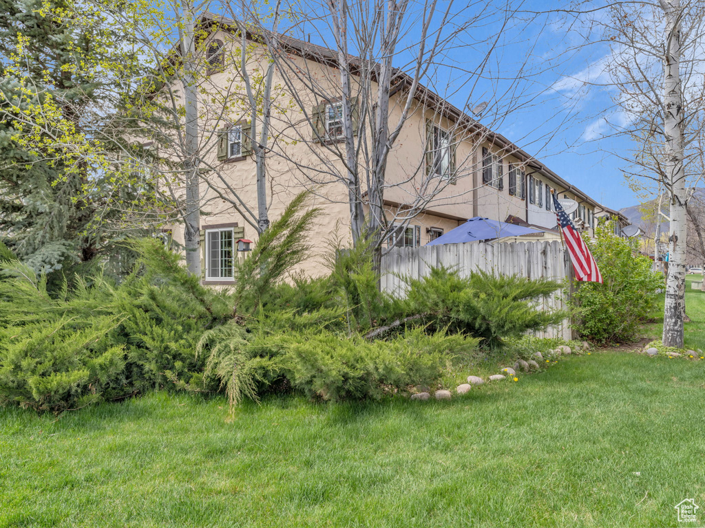 Exterior space with a lawn, fence, and stucco siding