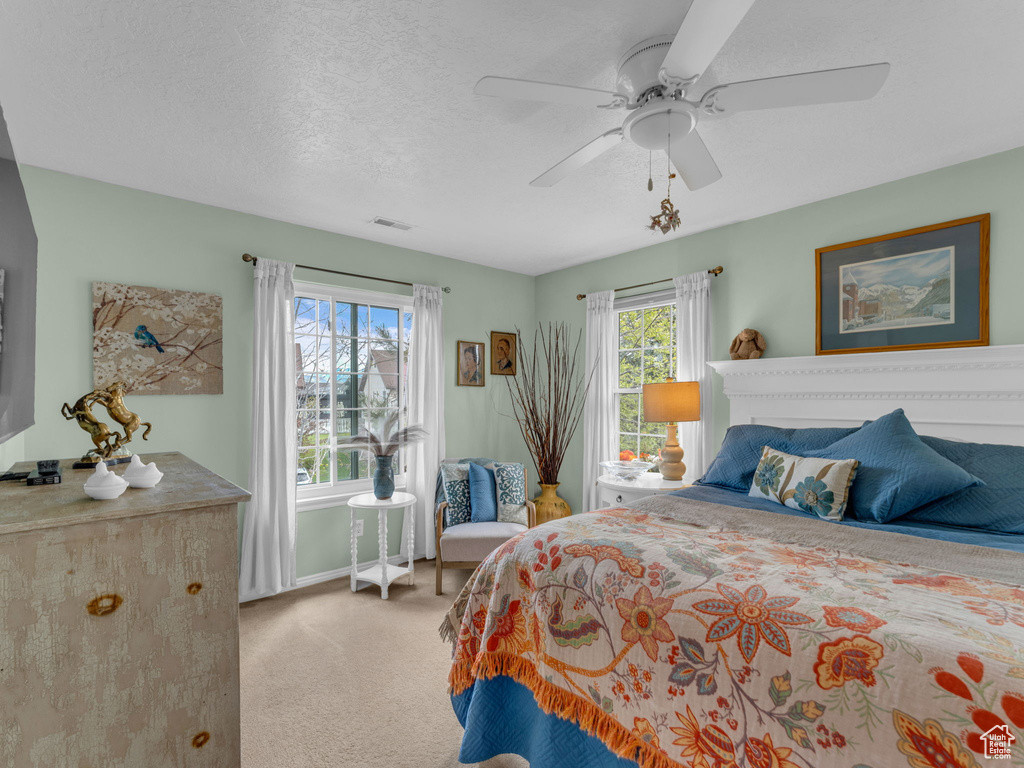 Carpeted bedroom with a ceiling fan, baseboards, visible vents, and a textured ceiling