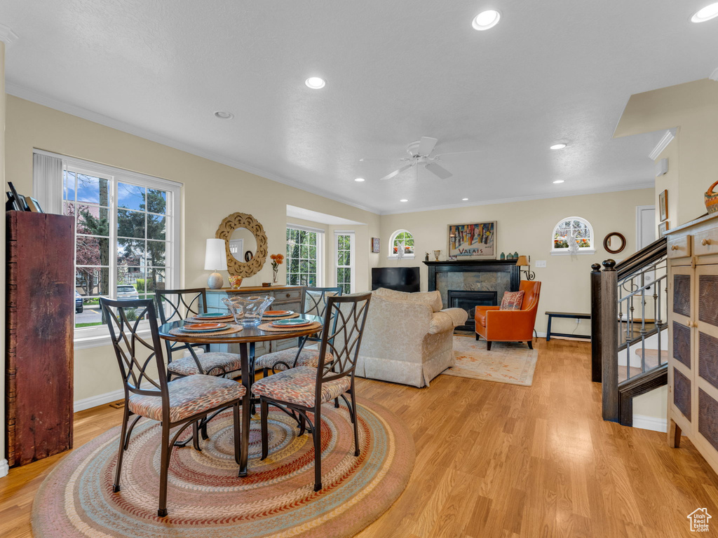 Dining space with a ceiling fan, baseboards, a glass covered fireplace, recessed lighting, and light wood-style flooring