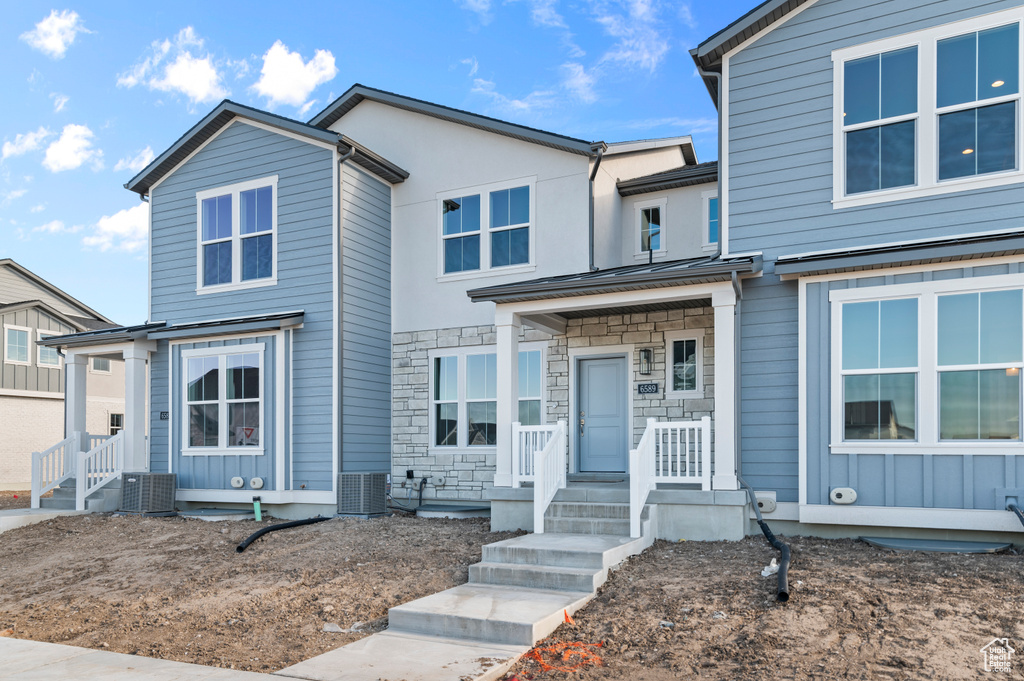 View of front of house featuring central AC unit and stone siding