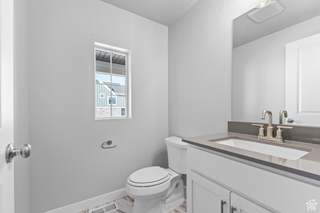 Bathroom featuring visible vents, baseboards, toilet, and vanity