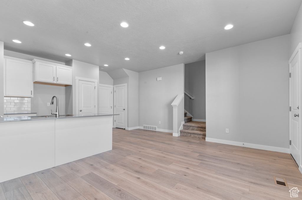 Unfurnished living room featuring a sink, recessed lighting, and visible vents