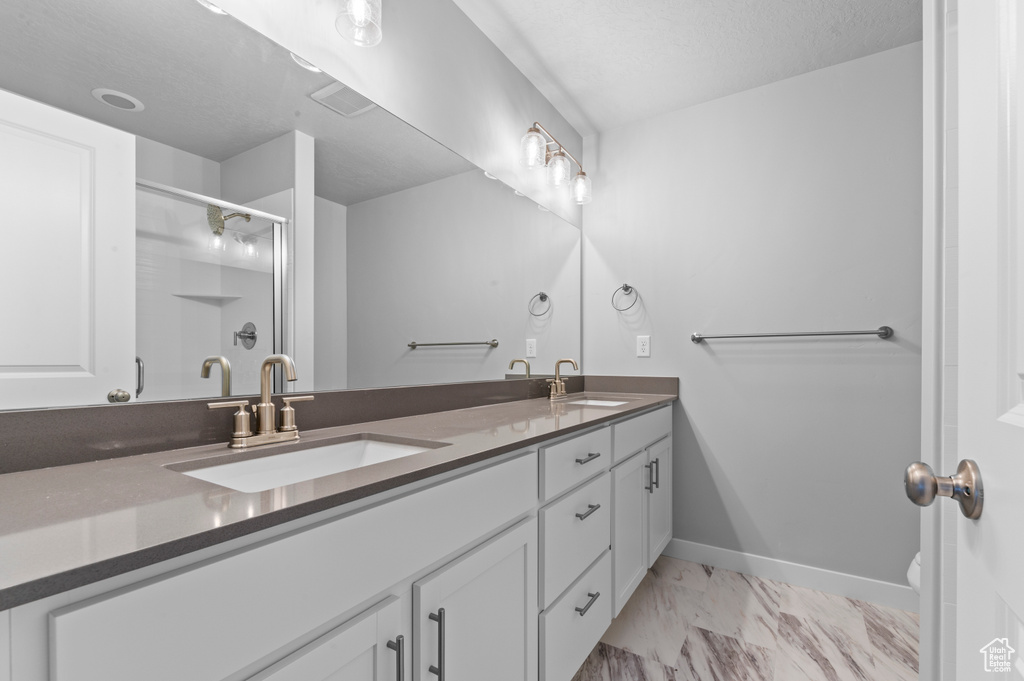 Full bathroom with double vanity, a shower stall, a sink, and marble finish floor