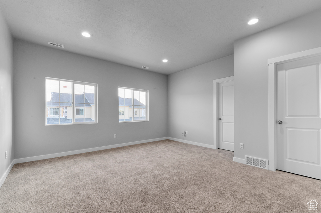 Empty room featuring visible vents, carpet flooring, baseboards, and recessed lighting