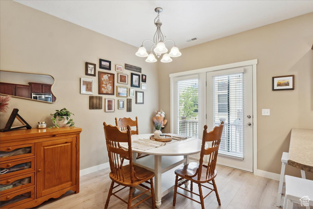 Dining area with visible vents, light wood finished floors, baseboards, and an inviting chandelier