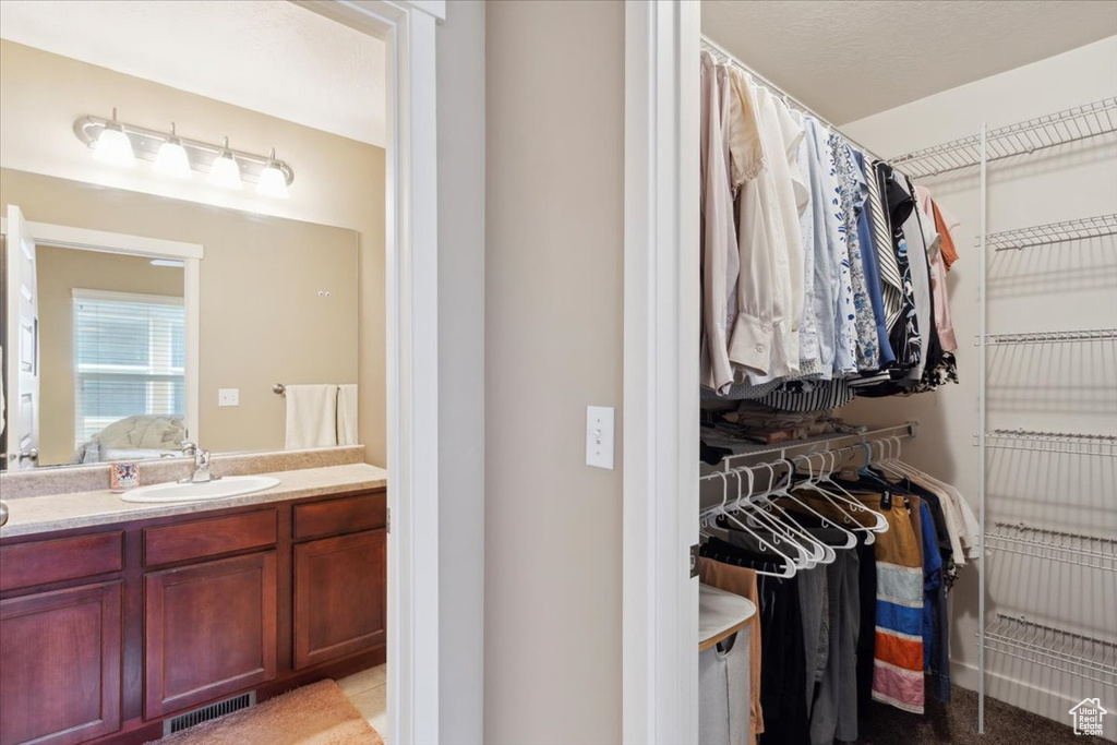Full bathroom featuring connected bathroom, visible vents, a walk in closet, and vanity