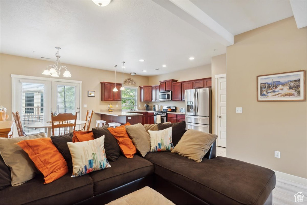 Living room with recessed lighting, baseboards, a notable chandelier, and light wood finished floors