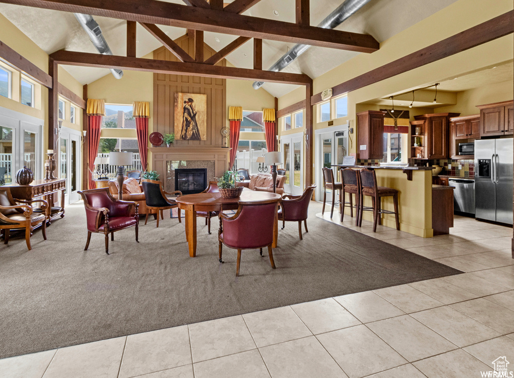 Dining area with beamed ceiling, light carpet, a glass covered fireplace, and light tile patterned flooring
