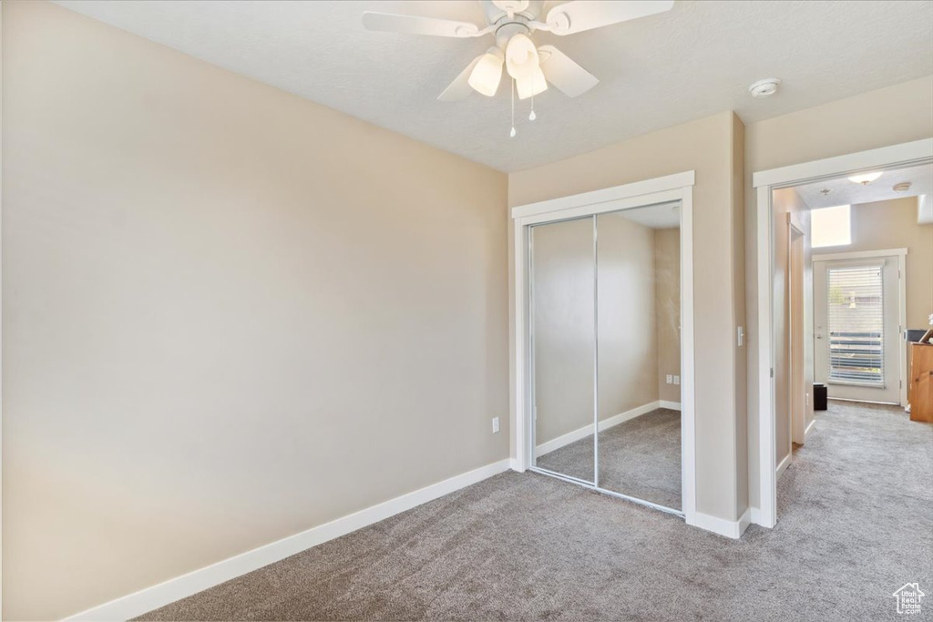 Unfurnished bedroom with baseboards, ceiling fan, carpet, and a closet