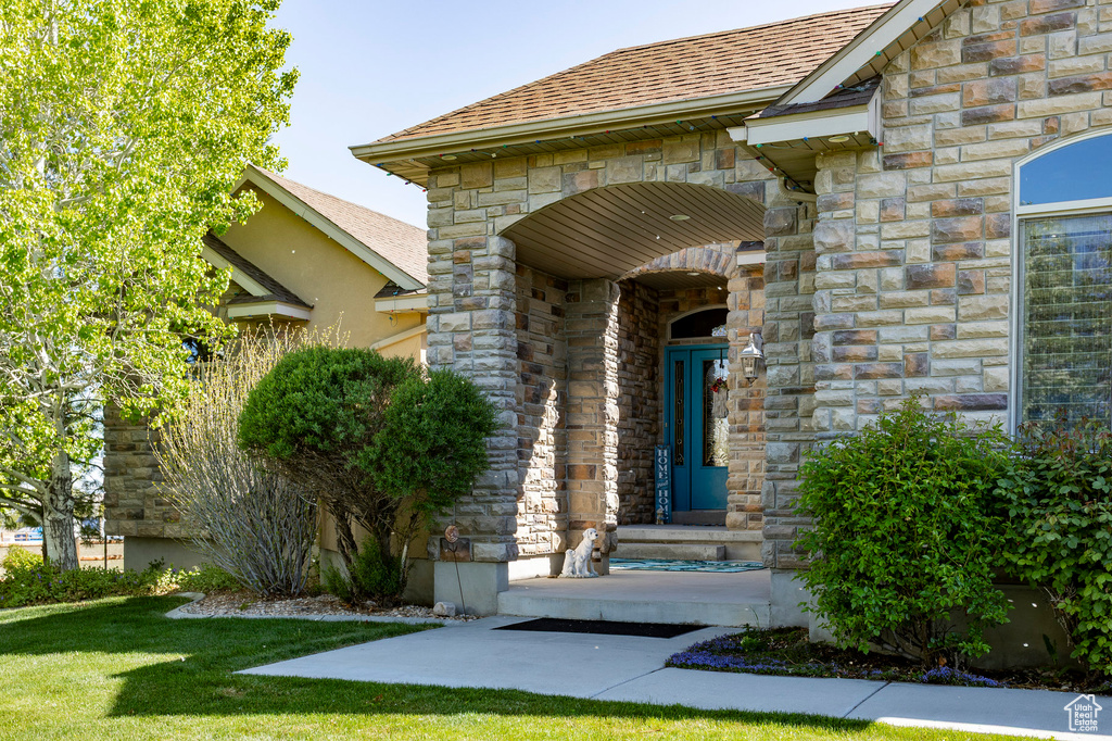 Entrance to property with a yard and stone siding