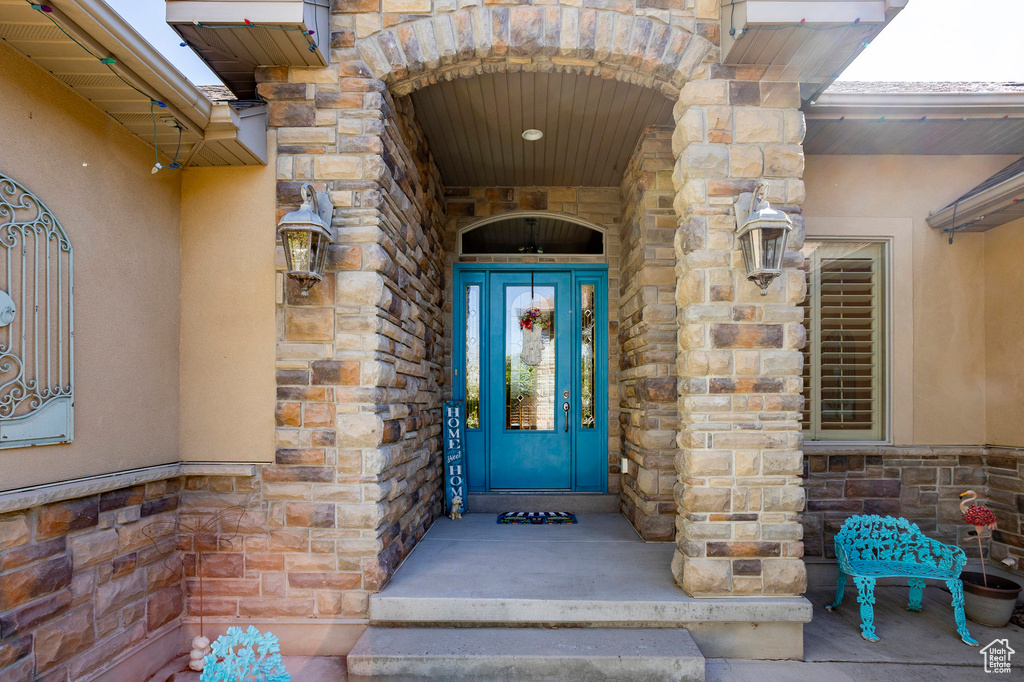 Doorway to property featuring stucco siding and stone siding