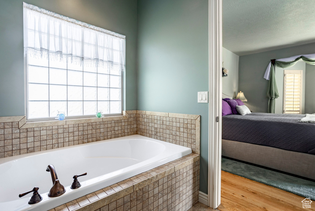 Full bathroom with wood finished floors, connected bathroom, and a bath