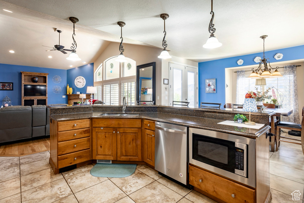 Kitchen featuring brown cabinets, a sink, built in microwave, open floor plan, and stainless steel dishwasher
