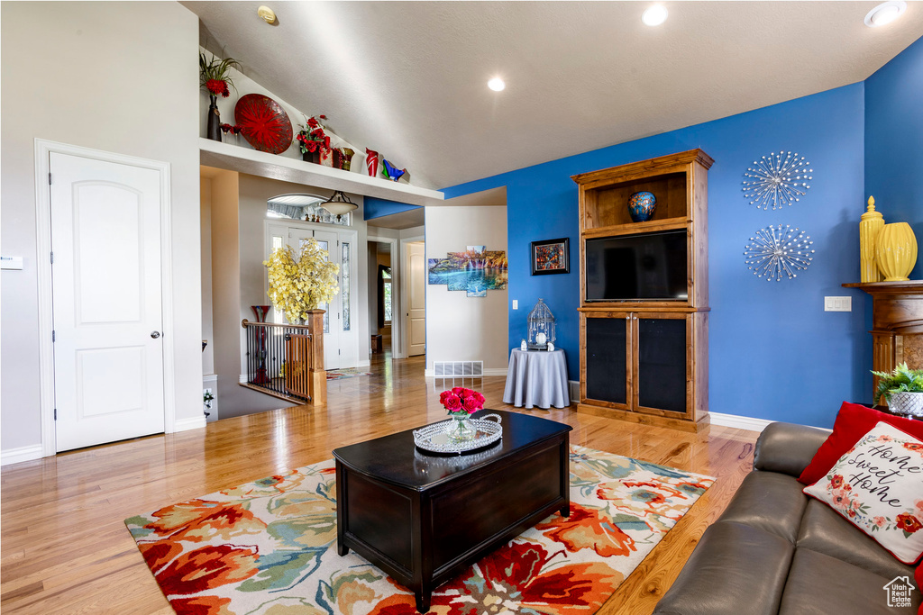 Living area featuring visible vents, wood finished floors, baseboards, recessed lighting, and vaulted ceiling