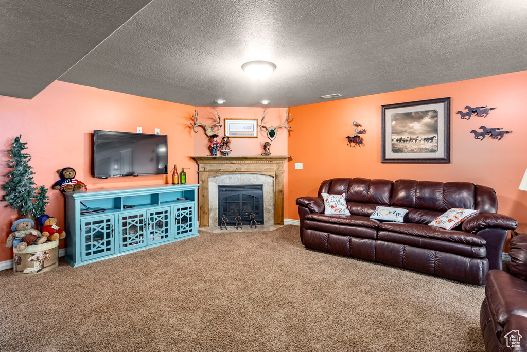 Carpeted living area with baseboards, a fireplace, a textured ceiling, and visible vents