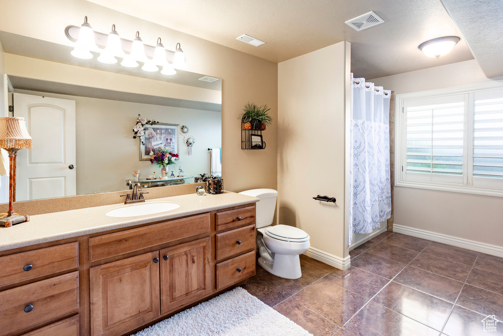 Full bath with visible vents, baseboards, toilet, and vanity