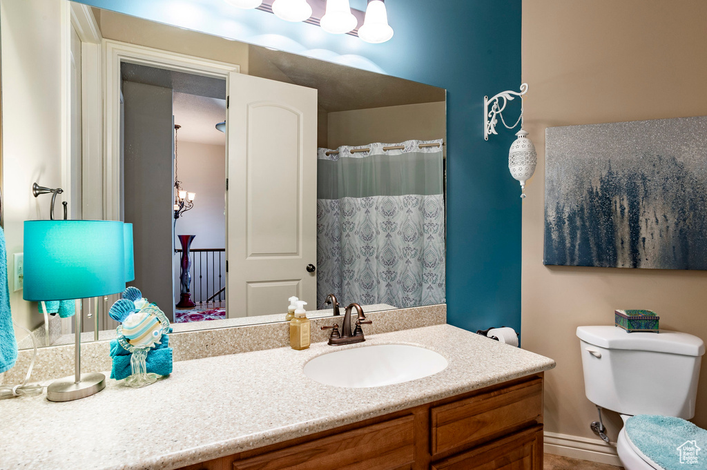 Bathroom featuring vanity, toilet, curtained shower, and a chandelier