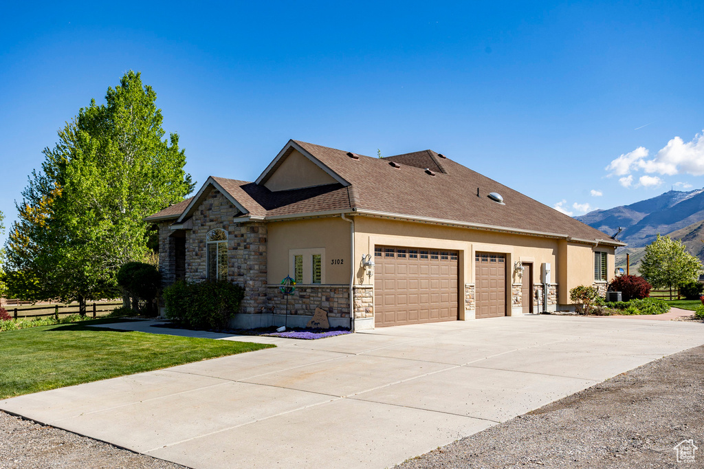 View of front facade featuring stone siding, a garage, stucco siding, a front yard, and concrete driveway