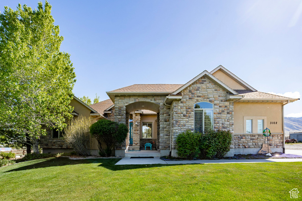 View of front of home featuring stone siding and a front lawn