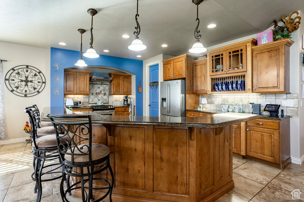 Kitchen featuring brown cabinetry, a kitchen island, tasteful backsplash, and stainless steel appliances