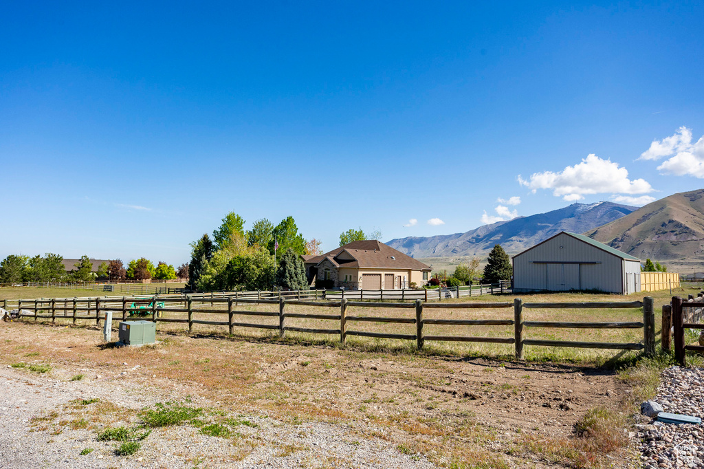 View of yard featuring an enclosed area, a mountain view, an outbuilding, and a rural view