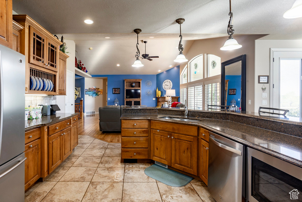 Kitchen with a sink, hanging light fixtures, brown cabinetry, and stainless steel appliances