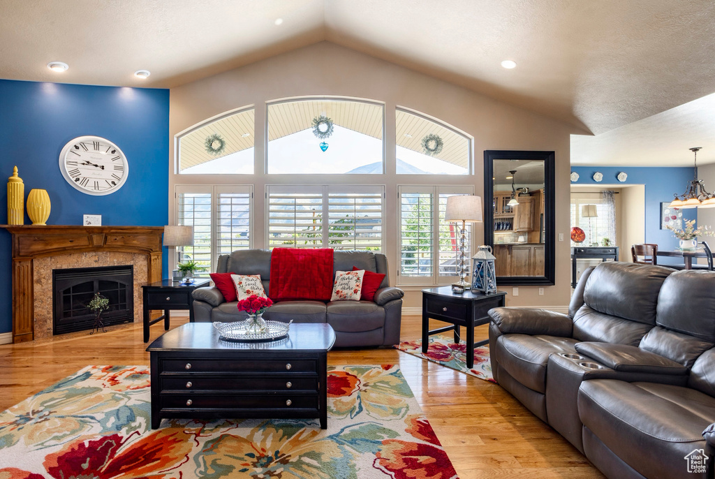 Living area with a fireplace, wood finished floors, and lofted ceiling