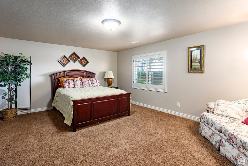 Bedroom featuring baseboards, a textured ceiling, and light colored carpet