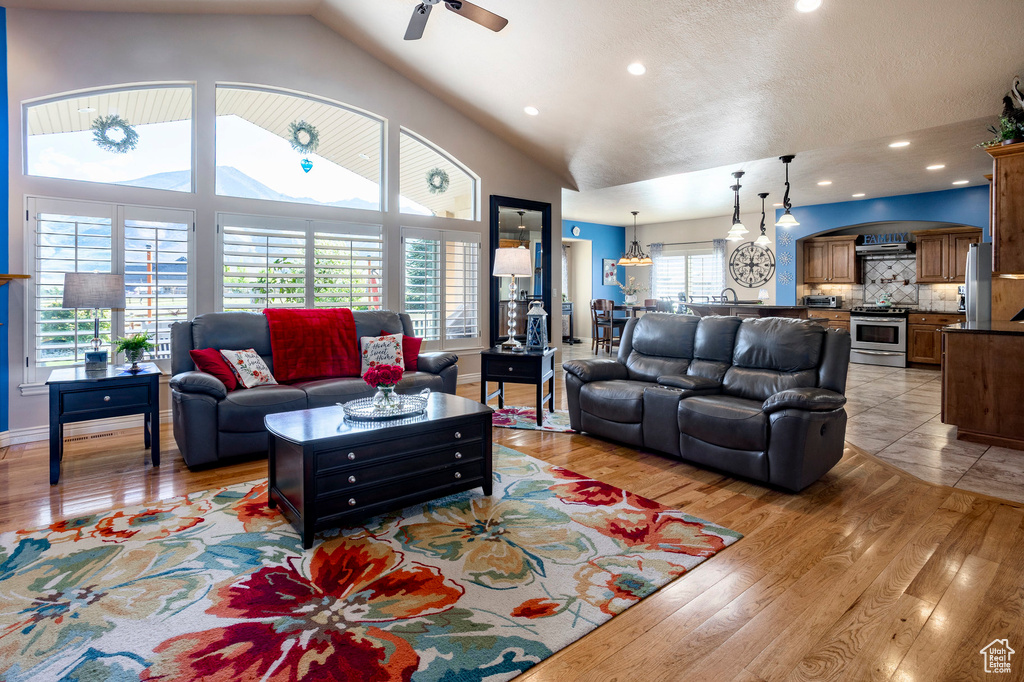 Living room with vaulted ceiling, light wood-style flooring, ceiling fan, and recessed lighting
