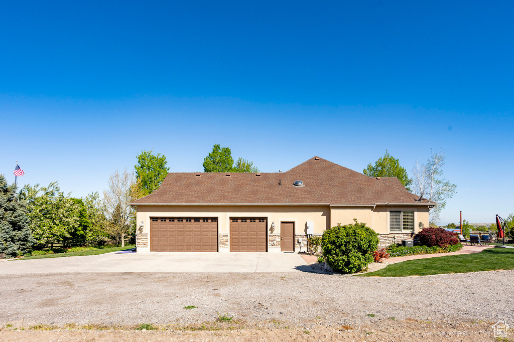 Single story home with roof with shingles, stone siding, a garage, stucco siding, and driveway