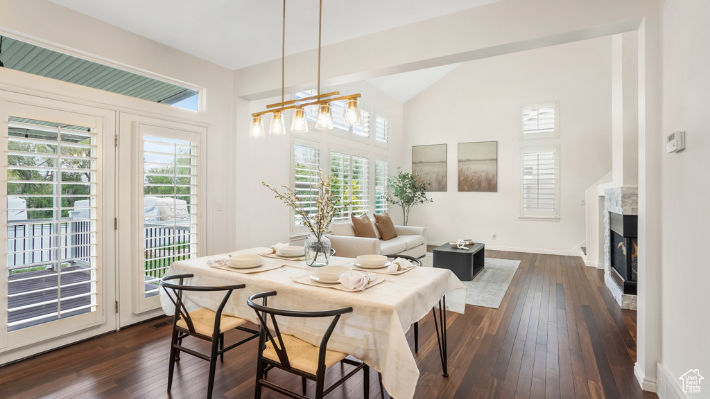 Dining area featuring baseboards, a chandelier, dark wood-style floors, and a high end fireplace