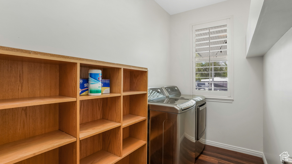 Clothes washing area with laundry area, washer and clothes dryer, baseboards, and dark wood finished floors