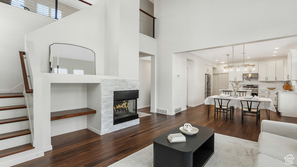 Living area featuring baseboards, visible vents, dark wood-style floors, and a towering ceiling