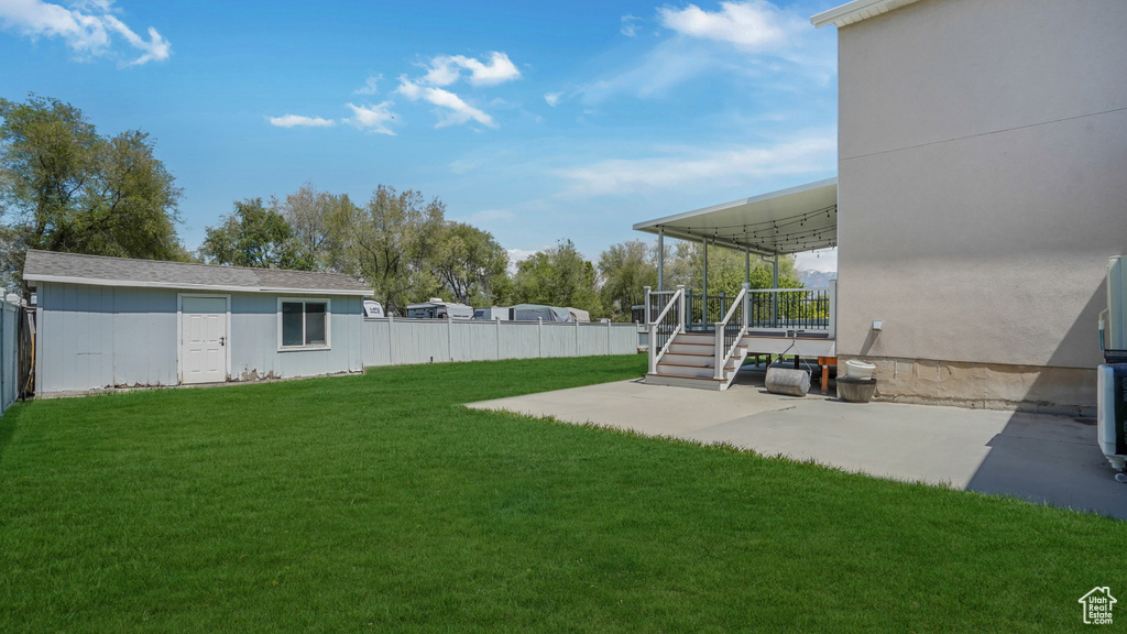 View of yard with fence, a patio, an outdoor structure, and a wooden deck