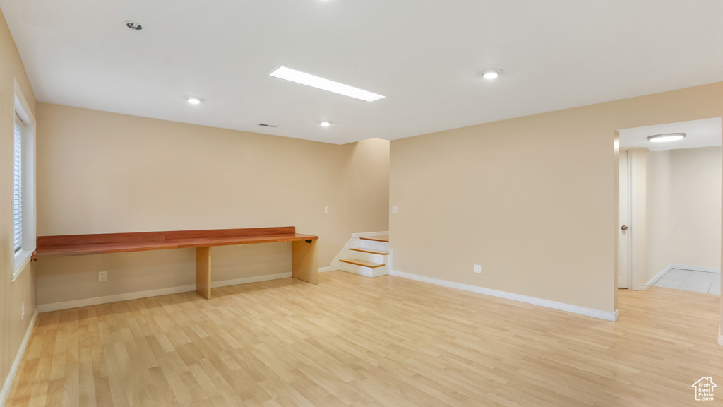 Unfurnished room featuring baseboards, recessed lighting, light wood-style flooring, and stairs