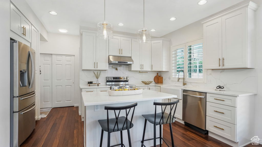 Kitchen with appliances with stainless steel finishes, decorative backsplash, under cabinet range hood, and recessed lighting