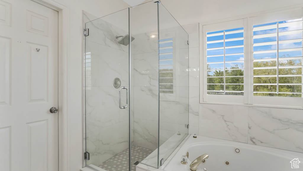 Bathroom featuring a tub with jets and a marble finish shower
