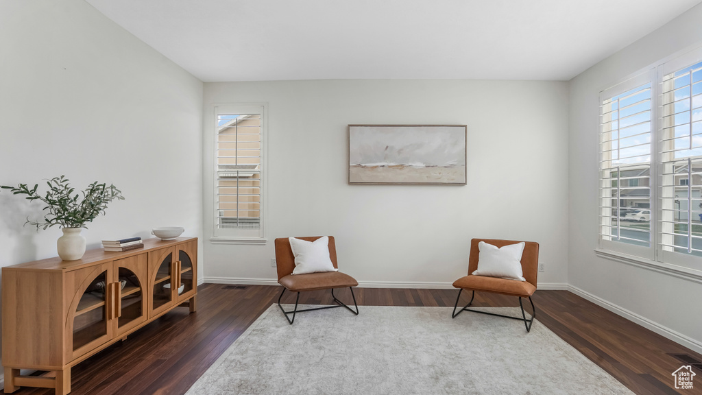 Living area featuring baseboards, visible vents, a healthy amount of sunlight, and wood finished floors