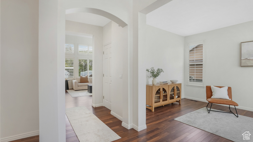 Corridor featuring dark wood-style flooring, arched walkways, and baseboards