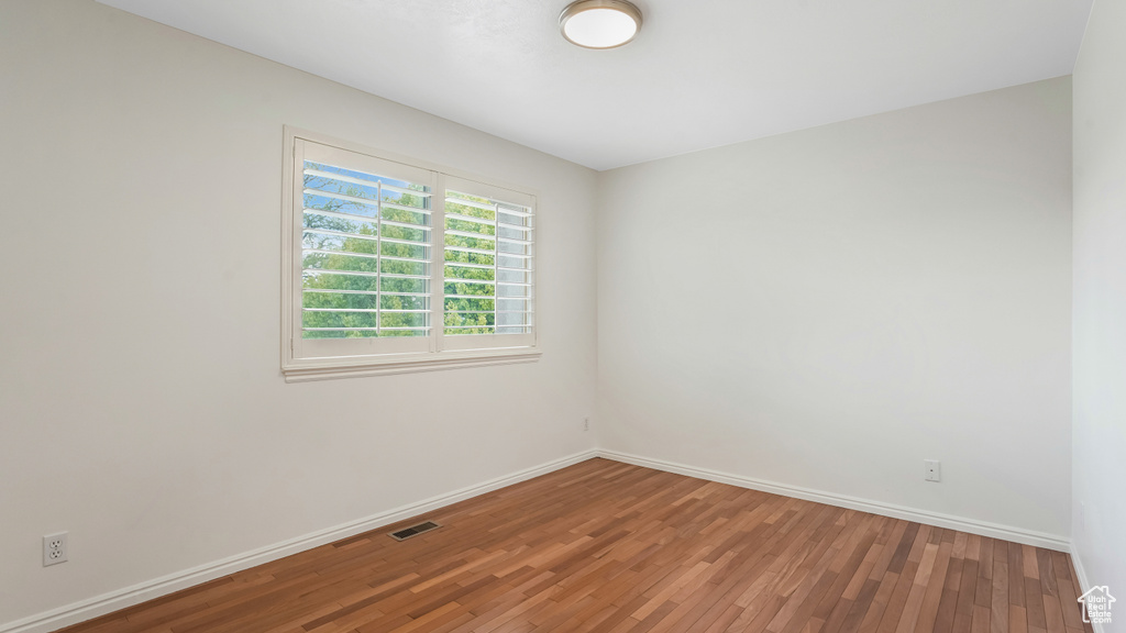 Unfurnished room with baseboards, wood finished floors, and visible vents