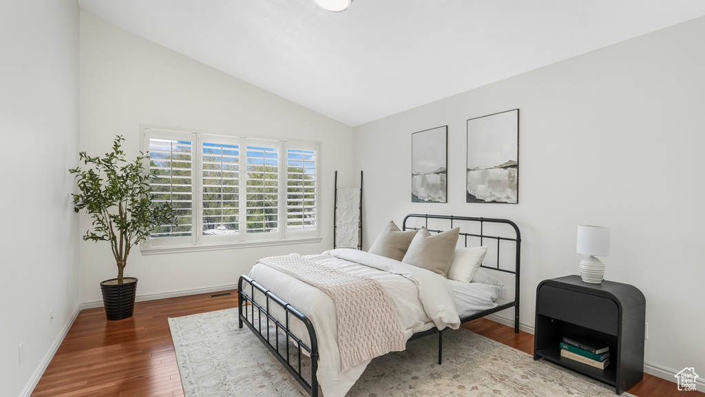 Bedroom featuring baseboards, wood finished floors, and vaulted ceiling