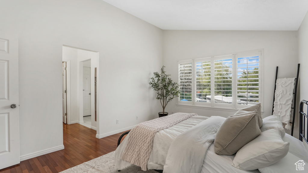 Bedroom with baseboards, high vaulted ceiling, and wood finished floors
