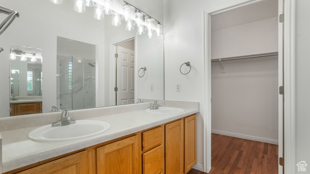 Full bath featuring double vanity, a shower stall, and a sink