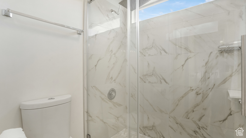 Full bathroom with a marble finish shower and toilet