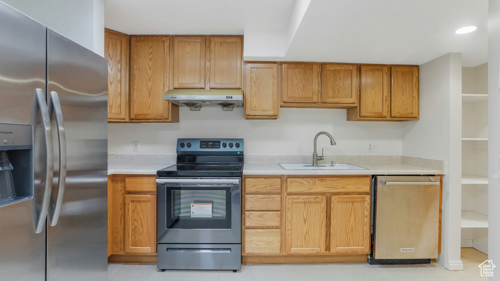 Kitchen featuring a sink, appliances with stainless steel finishes, under cabinet range hood, and light countertops