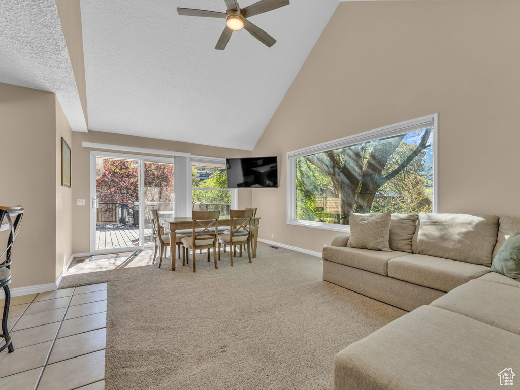 Living area with a ceiling fan, high vaulted ceiling, a wealth of natural light, and baseboards