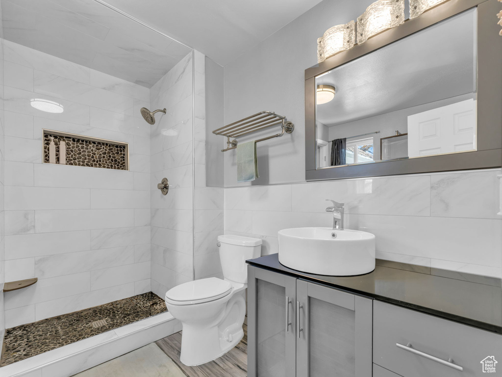 Full bathroom featuring toilet, tile walls, a tile shower, and vanity